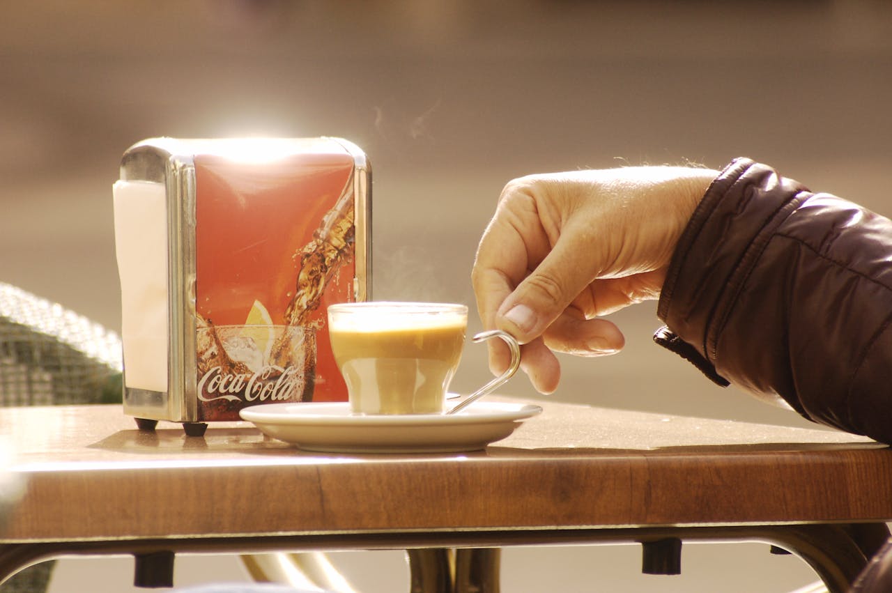 Hand holding coffee at an outdoor café in Murcia, Spain, enhancing a moment of warmth and relaxation.